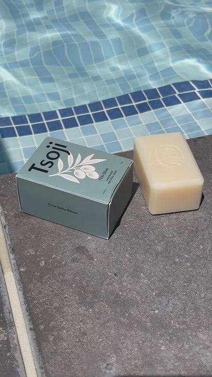 A video shot next to a pool in natural light showing Tsoji handmade all natural soaps Tsoji mountain green tea soap bar, Tsoji Ginseng Vitality soap bar, Tsoji Moongrass Harmony soap bar, Tsoji Shou Wu and Ginger soap bar, and Tsoji 72% Olive Soap bar one by one